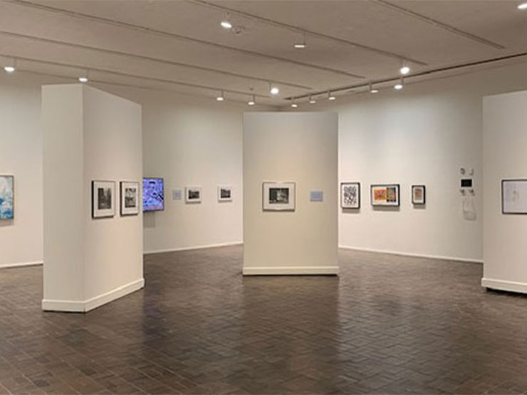 Photos hang on the spare, white walls in an art gallery.