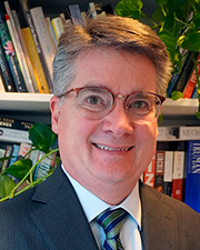 Man standing close to camera wearing dark glasses, suit and tie.