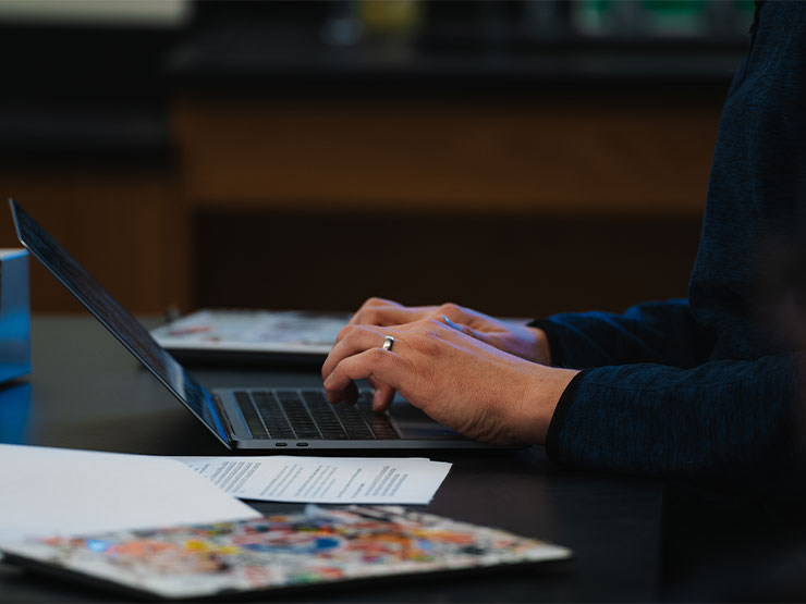 A close-up image of hands typing on a laptop.