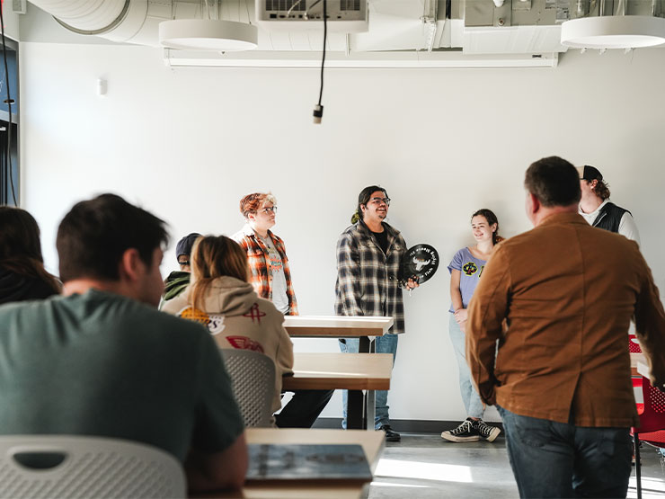 A group of college students present their creations in the campus Makerspace lab.