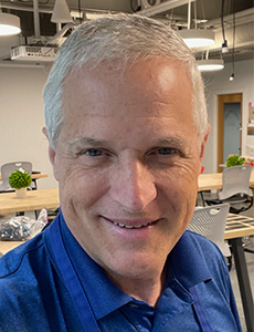 Profile image of Eric Schwartz, Makerspace Technician, posing wearing blue shirt in laboratory setting.