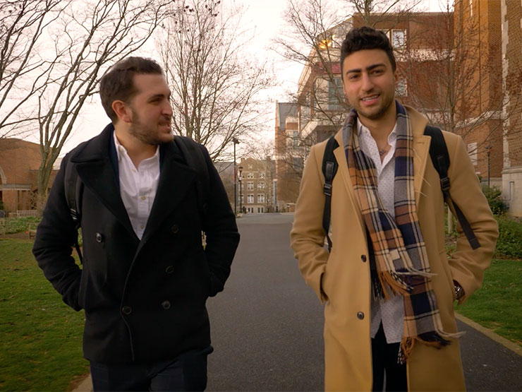 Two adults chat while walking down academic row in the winter on the campus of Muhlenberg College.