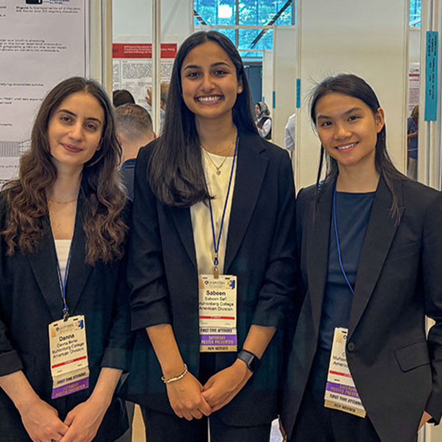 College student Sabeen Safi stands alongside two fellow student researchers at a conference.