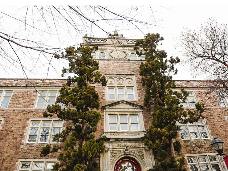 A pair of tall conifers frame the entrance of Ettinger Hall on the Muhlenberg College campus.