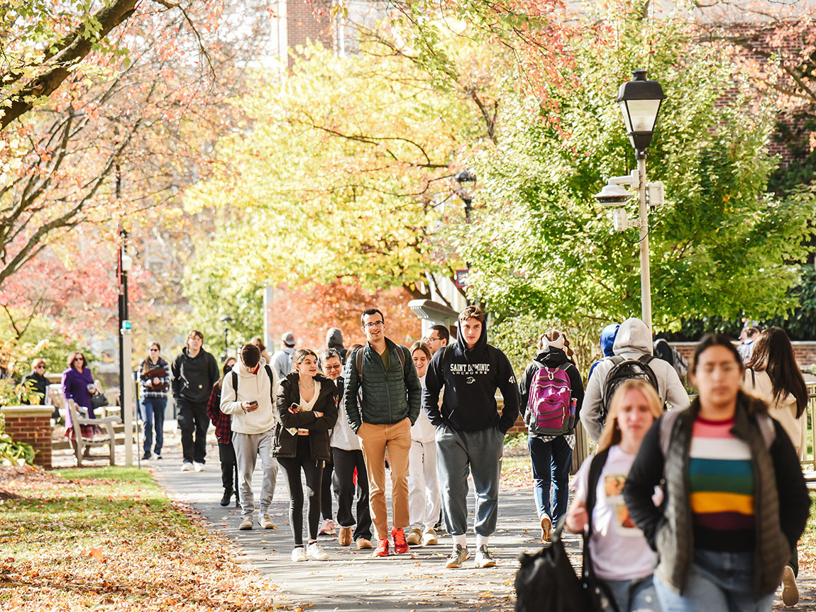 College students walk down Muhlenberg's Academic Row surrounded by bright fall foliage