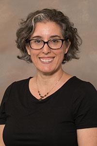 A headshot of a college professor in a black shirt wearing glasses