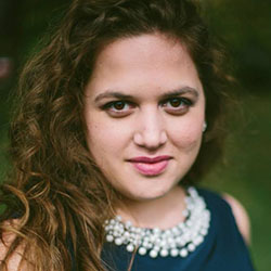 A college professor with long, dark, curly hair and a big necklace on